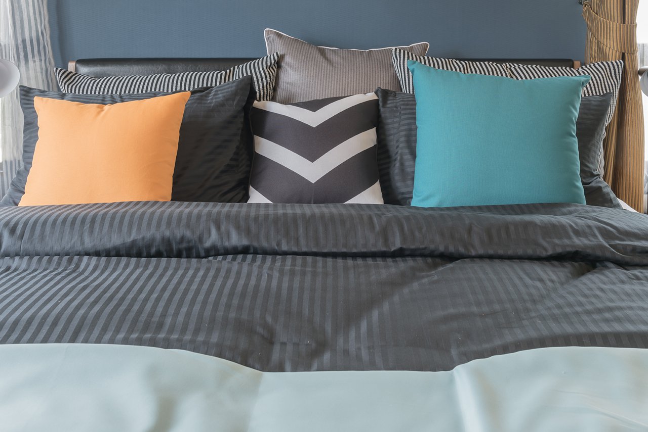 colorful pillows on dark color bed in modern bedroom
