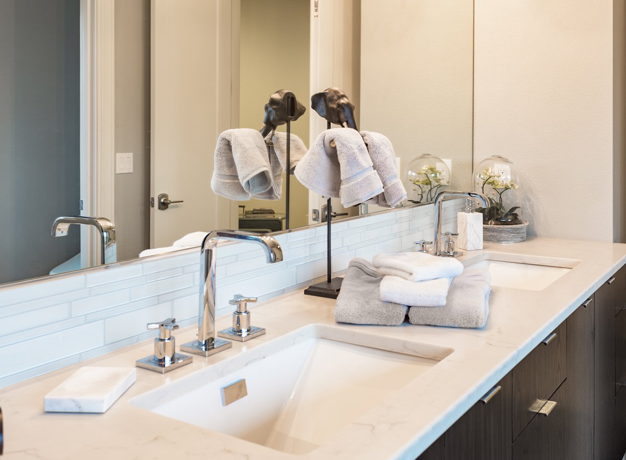 Bathroom detail in new luxury home: vanity with cabinet. Dual sinks and counter decorated with towels